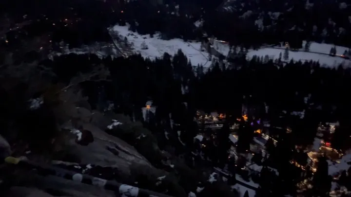 A snowy Yosemite landscape and distant lights at dusk.